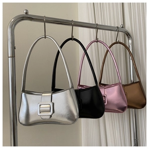 Fila de bolsos de hombro metalizados en plata, negro, rosa y bronce colgados en soporte