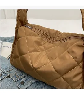 Close-up of brown quilted puffer shoulder bag with white contrast stitching details