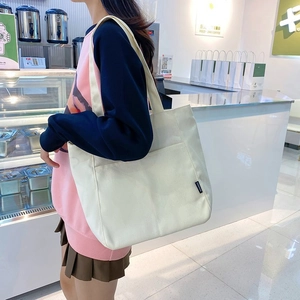 Minimalist white canvas tote bag with fashion label shown in a modern cafe setting