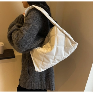 Detailed view of white quilted padded tote bag on shoulder for autumn winter look