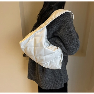 Detailed view of white quilted shoulder bag with rhombus texture worn by a model