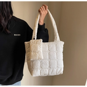 Detail of white quilted nylon tote bag with plush square stitching and small zip pouch