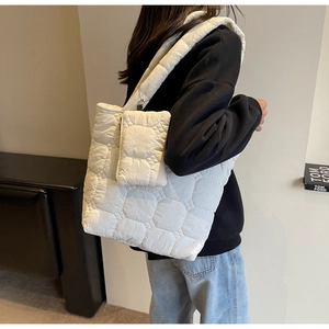 Detail of white quilted tote bag with matching coin purse shown on model's shoulder