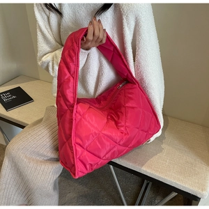 Detail of the rose red quilted tote bag featuring padded diamond patterns and zipper closure