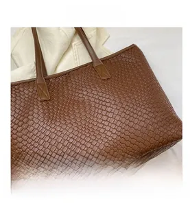 Detailaufnahme der dunkelbraunen geflochtenen PU-Ledertextur dieser modischen Tasche