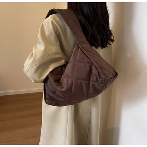 Close-up of brown quilted tote bag on model showing diamond texture and large capacity