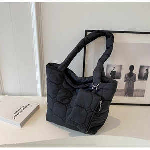 Macro detail of black quilted tote bag with matching zippered pouch and silver chain