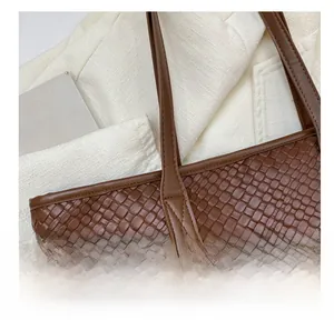 Nahaufnahme der gewebten braunen Ledertextur und Nähte an der minimalistischen Shopper