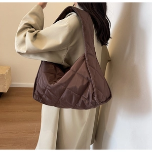Close-up of quilted dark brown oversized shoulder bag with shiny padded nylon finish