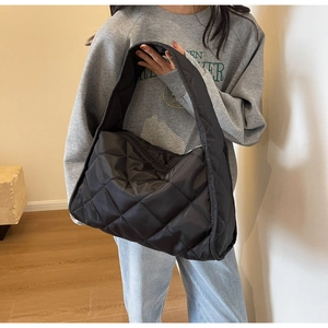Detailed view of the black quilted puffer shoulder bag showing large rhombic texture