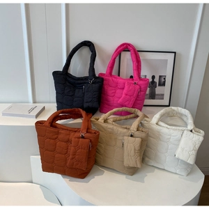 Close-up of quilted bubble textured tote bags in five vibrant colors on a display stand
