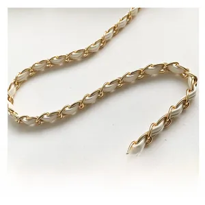 Detail of elegant gold metal chain strap interwoven with premium white leather texture