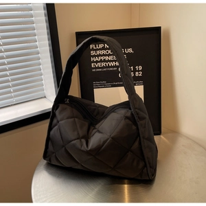 Close-up of black quilted hobo bag featuring premium nylon texture and wide shoulder strap