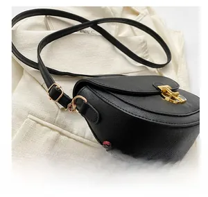 Close-up of black lychee grain leather crossbody bag with golden triumphal arch lock