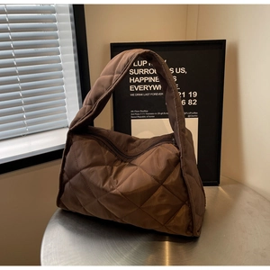 Detailed view of dark brown quilted puffer tote bag on a metallic silver surface