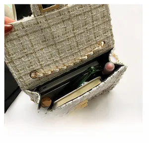 Interior capacity display of a beige tweed crossbody bag with chain strap and gold clasp