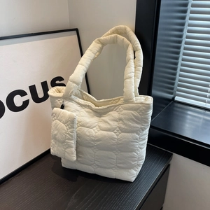 Minimalist cream quilted tote bag with matching mini pouch on dark wood surface