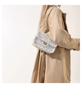 Detail of the white tweed crossbody bag with gold chain strap on a trench coat