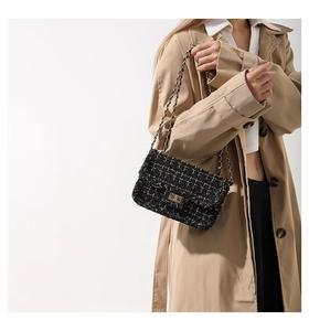 Detail of classic black tweed crossbody bag with golden chain strap and metal lock closure