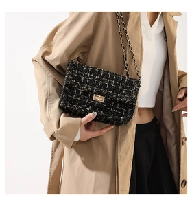 Close-up of elegant black tweed crossbody bag with gold metal chain and twist lock clasp