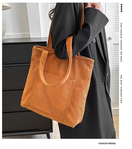 Detail of soft corduroy texture and wide shoulder strap on large orange tote bag