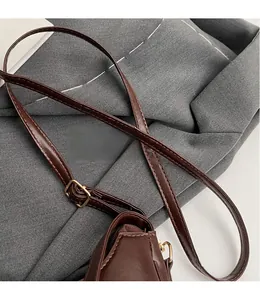Detail view of the brown vintage shoulder bag showing adjustable strap and gold buckle