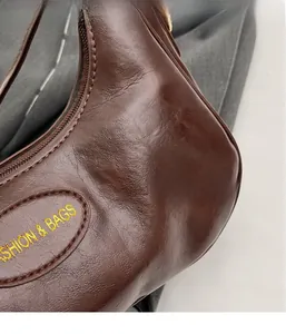 Close-up of brown faux leather texture with Fashion & Bags embroidery on handle bag