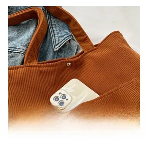 Close-up of brown corduroy tote bag featuring a functional front pocket for smartphones