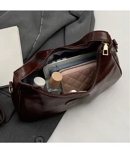 Detail view of large capacity dark brown crossbody bag interior holding wallet and phone