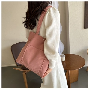 Detail of pink corduroy tote bag showing thick texture and front pocket on model