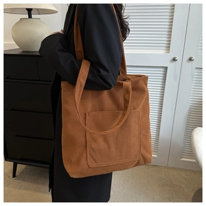 Detailed view of brown corduroy tote bag showing textured vertical stripes and outer pocket