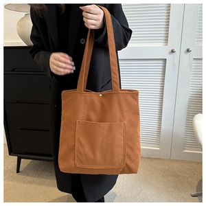 Detailed close-up of brown corduroy tote bag with magnetic snap and front pocket