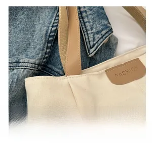 Detailansicht der beigen Nylon-Canvas-Tasche mit braunem Lederetikett und feiner Verarbeitung