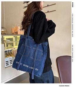 Blue denim tote bag with side pockets and white street style lettering on a casual model