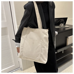 Cream corduroy tote bag showing spacious front pocket and metallic magnetic buckle detail