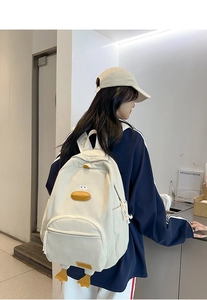 Detail view of cute white corduroy backpack with 3D duck features and orange feet