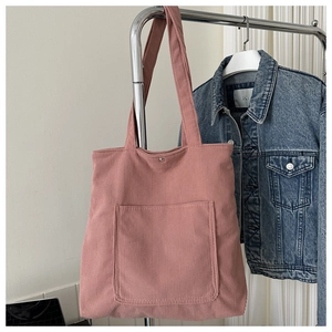 Detail view of pink corduroy tote bag featuring front pocket and magnetic closure
