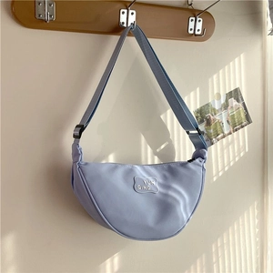 Detail of light blue crescent bag showing nylon fabric texture and YUN QING brand patch
