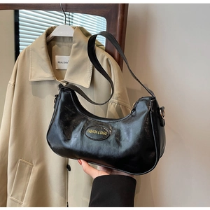 Detail of a black pleated crescent underarm bag with gold logo and metal zipper