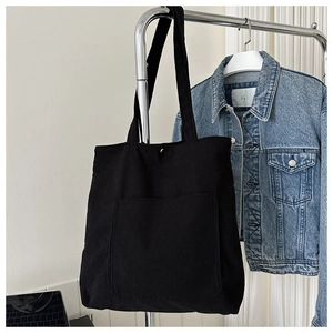 Detail of black corduroy tote bag showing ribbed texture and metal snap button closure