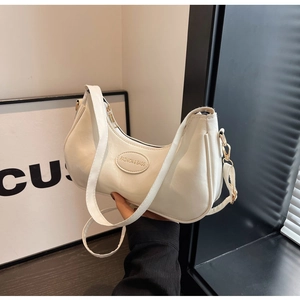 Close-up of cream hobo bag showing litchi texture and fashion logo plaque details