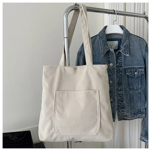 Detail showing the off-white corduroy tote bag texture and wide shoulder strap
