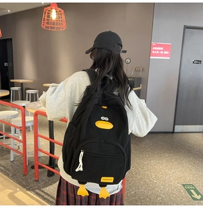 Detail view of the black corduroy backpack with cute cartoon duck design and fashion label