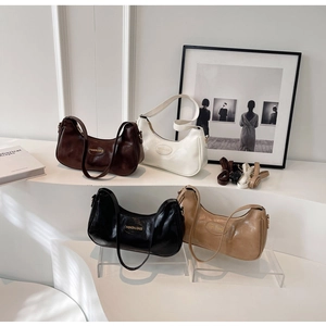 Detail of four stylish half-moon shoulder bags in brown, black, beige, and white colors