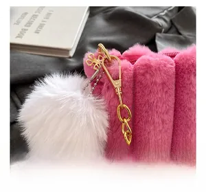 Detail of pink plush handbag with fluffy white ball charm and gold metal floral accents