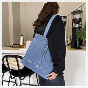 Fashionable denim tote bag with street style print and pocket design detail on a model