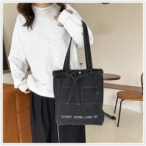 Detail of black washed denim tote bag with street style print and front pockets