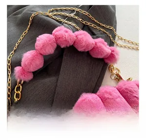 Detail showing plush pink faux fur texture and a unique decorative pom-pom handle