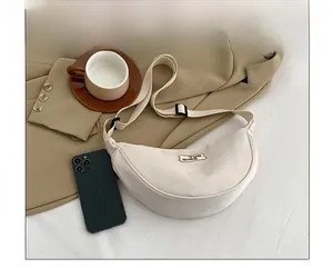 White nylon crescent crossbody bag next to a smartphone showing the actual product size