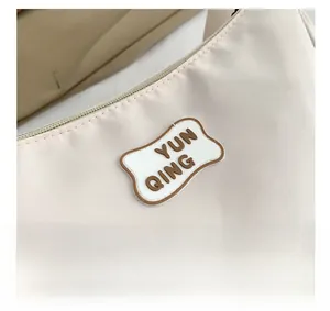 Macro detail of beige nylon shoulder bag with silver zipper and YUN QING logo patch